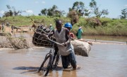 Zaccharia Roberto pushes his bicycle laden with charcoal across a flooded river near Nhamatanda, Mozambique. Cyclone Idai has disrupted infrastructure across the country, impacting livelihoods and hampering aid efforts. Photo: Tommy Trenchard / Concern Worldwide