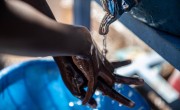 Trevor (4) washes his hands. Ambeza Idd, (35) (blue vest) mans the hand washing station. Kibera Slum, Nairobi, Kenya Photo: Ed Ram / Concern Worldwide