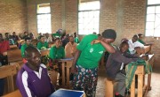 A Concern Care Group Volunteer demonstrating how to cough while protecting others from Covid-19 transmission. Photo: Maud Biton