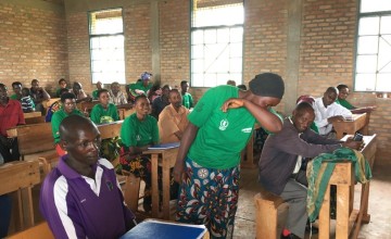 A Concern Care Group Volunteer demonstrating how to cough while protecting others from Covid-19 transmission. Photo: Maud Biton