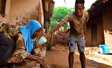 Marriam Jamali's son Bruno helps pour water on her hands while she washes them. They received soap as part of hygiene distribution to help prevent the spread of Covid-19 in Malawi.