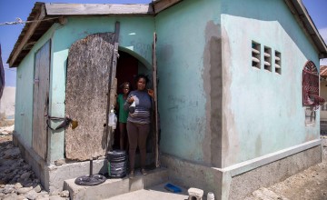Roseline, a dressmaker from Haiti, outside her home with her son