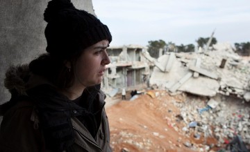 A young Syrian girl stares out at rubble