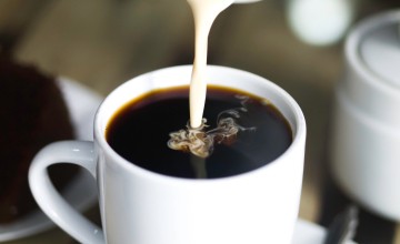 Milk being poured into a mug of coffee