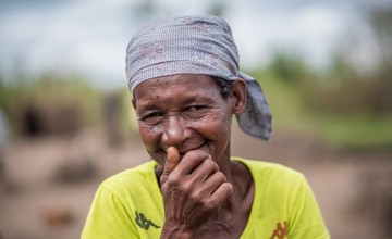 Joana Luis, 65, photographed with her family's pile of supplies received at a distribution in Ndeja, Mozambique. Photo: Tommy Trenchard