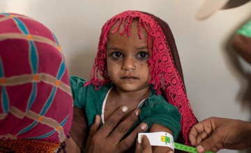 A child gets MUAC measurement assessed by a nutrition assistant. 