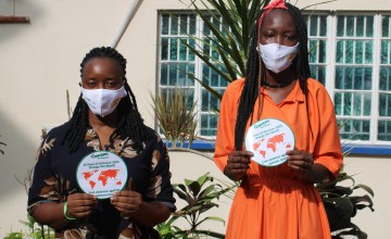 Two women holding up signs for End Violence Against Women