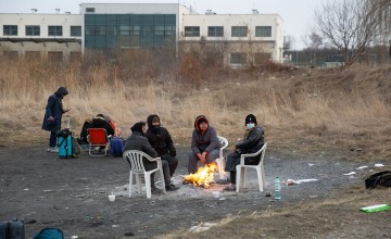 People sitting around small fire at Polish border