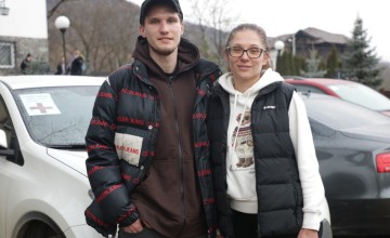 Mother and her son standing in front of cars
