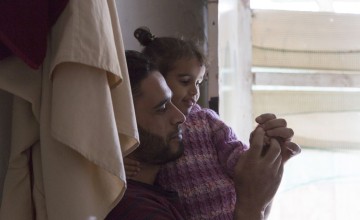 Syrian refugee Hassan* plays with his daughter Dalia* at home where he lives with his wife, children and his parents at an informal tented settlement in North of Lebanon.