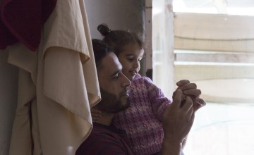 Syrian refugee Hassan* plays with his daughter Dalia* at an informal tented settlement in Lebanon. Photo: Dalia Khamissy