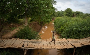 A man uses a small bridge to cross a river in Mikemani village, Tana River County. Photo: Zurich Flood Resilience Alliance/Concern Worldwide