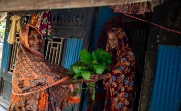 Asma Begum shares her produce that she has grown using the climate-smart techniques taught by Concern with her neighbour. Photo: Gavin Douglas