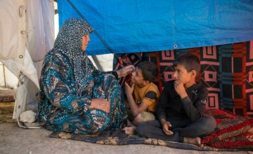 Shahinaz* and her grandsons sit in their tent at a camp  in north-west Syria following the 2023 earthquakes. Photo: Karam Al-Masri/Arete/DEC