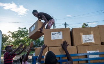 Esparanza Maria, a 25-year-old day worker from Nhamatanda, helps load boxes containing essential household supplies from a warehouse to a truck. The items will be distributed the next day in the village of Ndeja. "It makes me feel good to be able to help