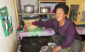 Jong Hyon Hwa turns on a tap with water supplied by Concern Worldwide’s gravity fed water supply system in Daesong, Singye, North Hwanghae, Democratic People’s Republic of Korea. Photo taken by Pae Ryong Il / Concern Worldwide.