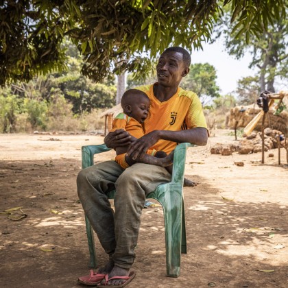 Alain* and baby Christian* in Ngata village outside their home on 22/02/22 Photo: Ed Ram/Concern Worldwide