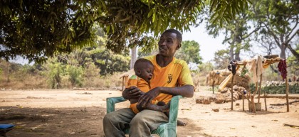 Alain* and baby Christian* in Ngata village outside their home on 22/02/22 Photo: Ed Ram/Concern Worldwide