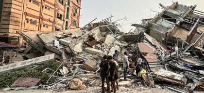 People stand past the debris of a collapsed building in Mandalay, Myanmar, on 28 March 2025 after the earthquake.