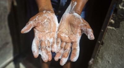 Rosette Mesalien washes her hands with liquid soap in front of their home in Cite Soleil slum a district of Port-au-Prince.
