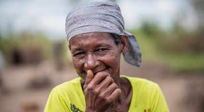 Joana Luis, 65, photographed with her family's pile of supplies received at a distribution in Ndeja, Mozambique. Photo: Tommy Trenchard