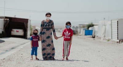 Sheren stands in the street outside their tent with her two daughters in Khanke camp. Photo: George Henton