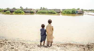 Children look across the floodwaters in Sindh province, Pakistan, where millions of people need urgent help. DEC charity Islamic Relief is providing emergency food and temporary shelter as families do all they can to keep safe and survive. Photo: Islamic Relief