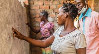 A woman does an exercise on the board at one of Concern’s projects in Manono, Tanganyika for illiterate women. Photo: Pamela Tulizo/Panos/Concern Worldwide