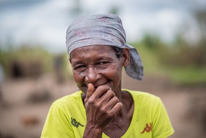 Joana Luis, 65, photographed with her family's pile of supplies received at a distribution in Ndeja, Mozambique. Photo: Tommy Trenchard